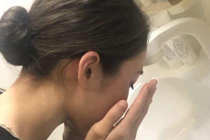 女性が洗面台で顔を洗っています。