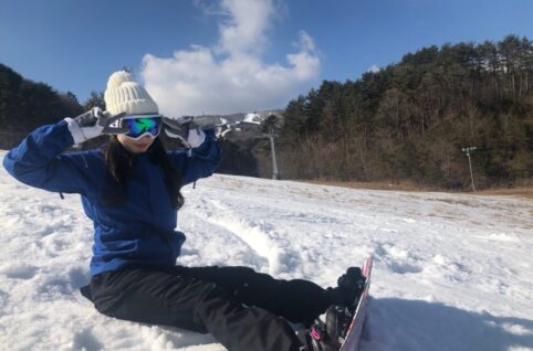 雪の中スノーボードに座る女性。