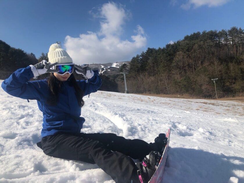 雪の中スノーボードに座る女性。