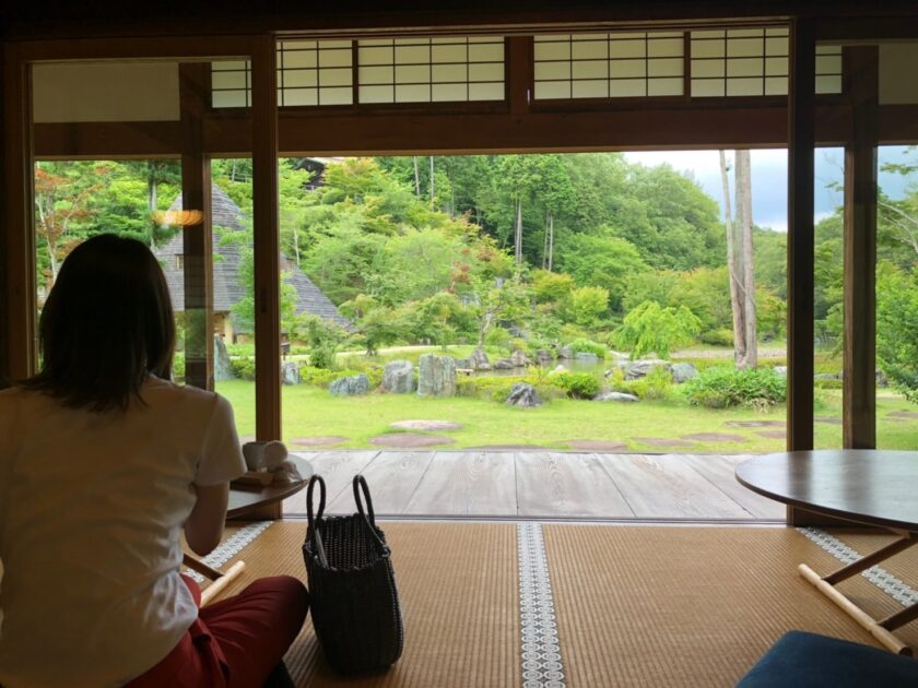 和室に座って庭を眺める女性。