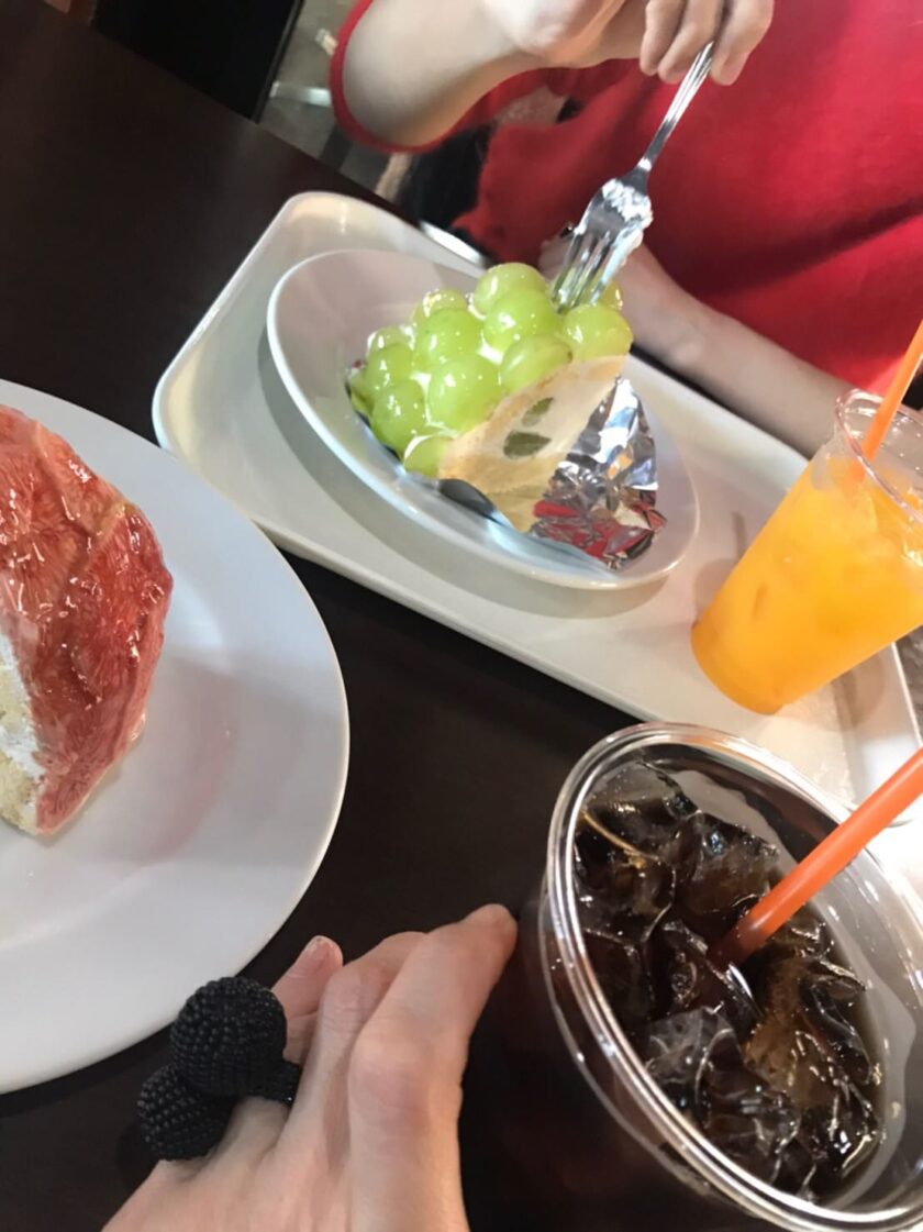 人が食べ物と飲み物の皿を持ってテーブルに座っています。