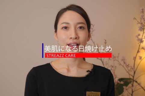 黒いシャツを着た女性が花の前に立っています。