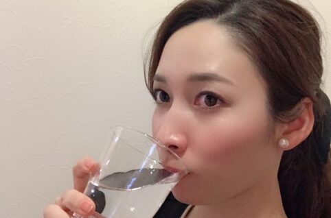 コップ一杯の水を飲む女性。