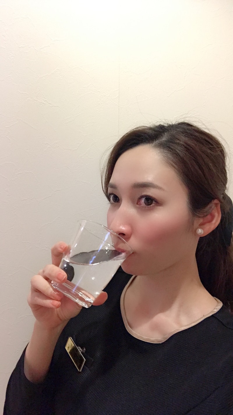 コップ一杯の水を飲む女性。