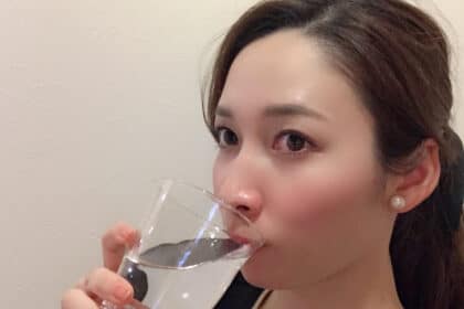 コップ一杯の水を飲む女性。